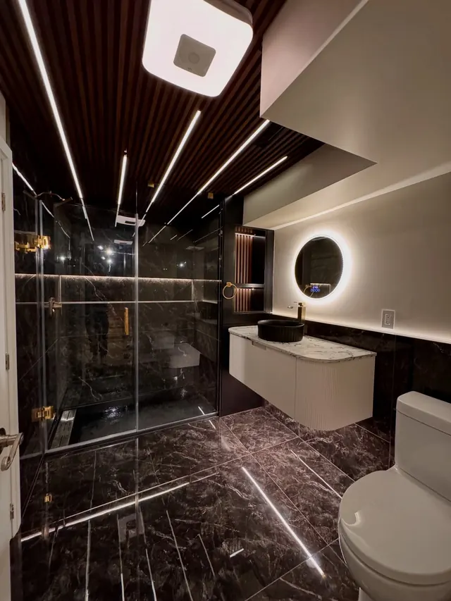 Dark marble bathroom with a ribbed timber ceiling.