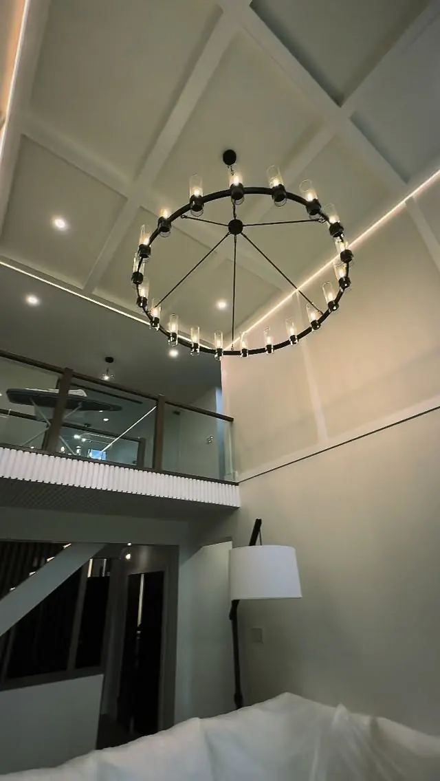 Double-height void with a coffered ceiling and a ring chandelier.