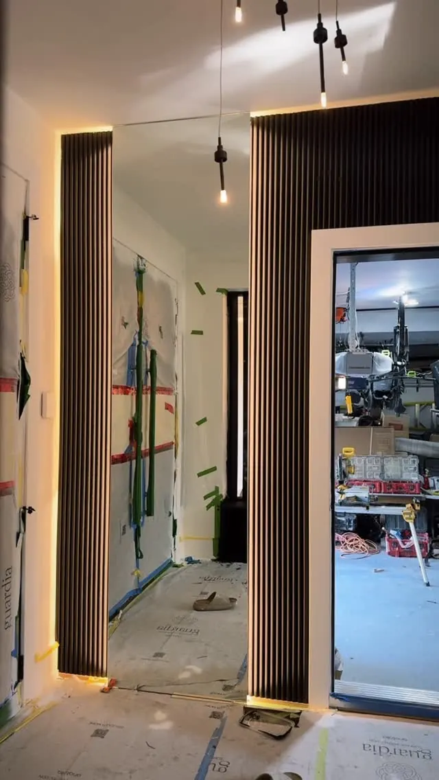 A hallway part-way through construction, protected and taped, with slat panelling installed.