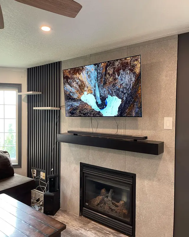 Dark media wall with a stone surround and concealed lighting.