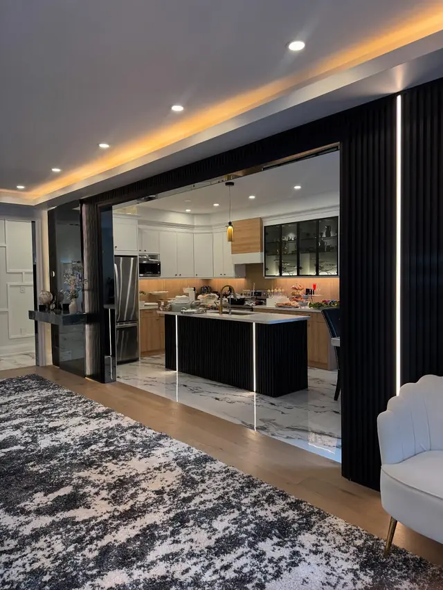 Open-plan living and kitchen through a dark framed opening.