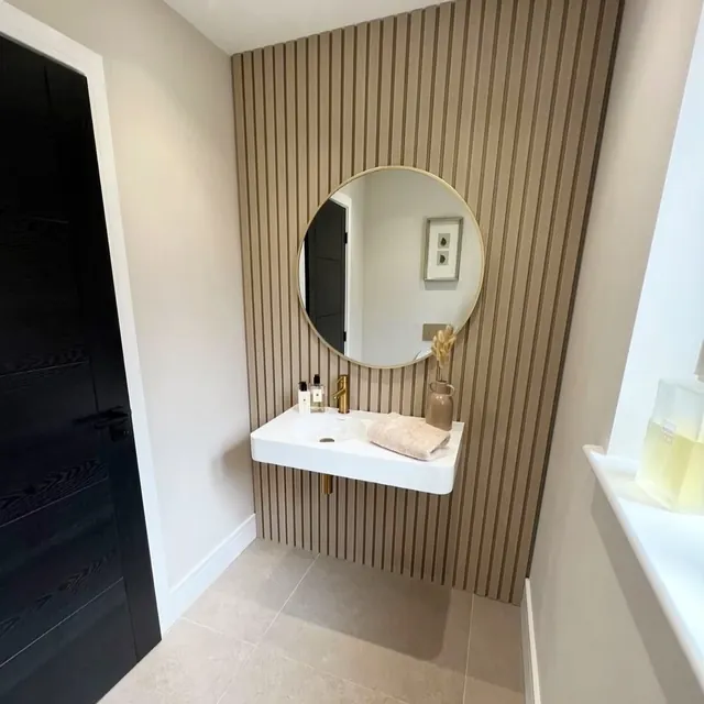 Powder room with ribbed timber panelling and a round mirror.